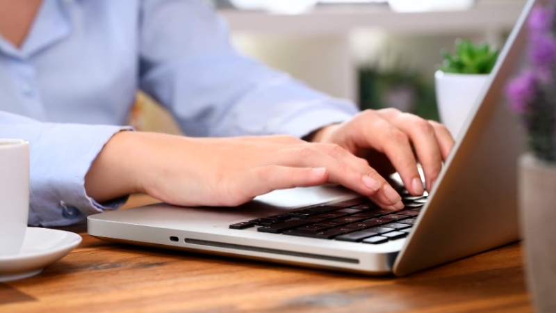 A person typing on a laptop, focused on building credibility through consistent public contributions