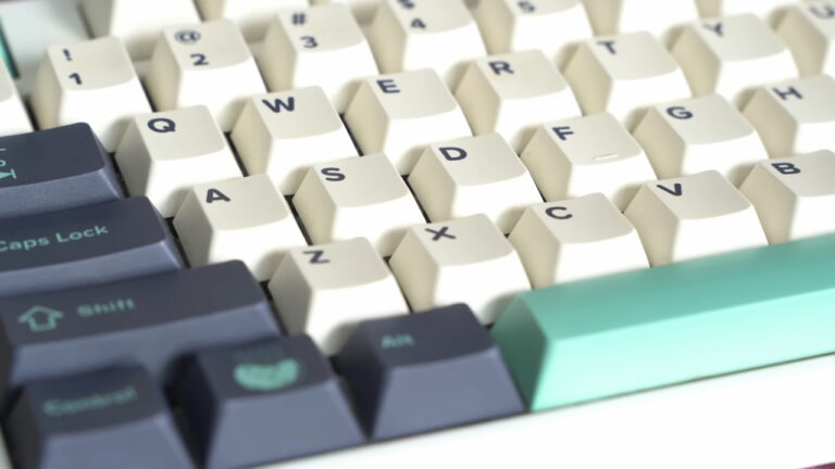 Close-up of a mechanical keyboard with white and dark gray keycaps, including the QWERTY and function keys
