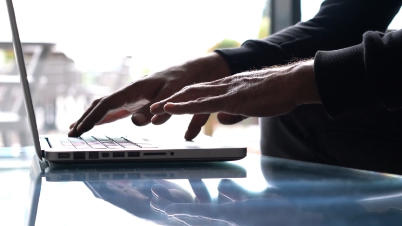 Close-up of hands typing on a laptop, symbolizing the need for more than just SEO in the modern digital landscape