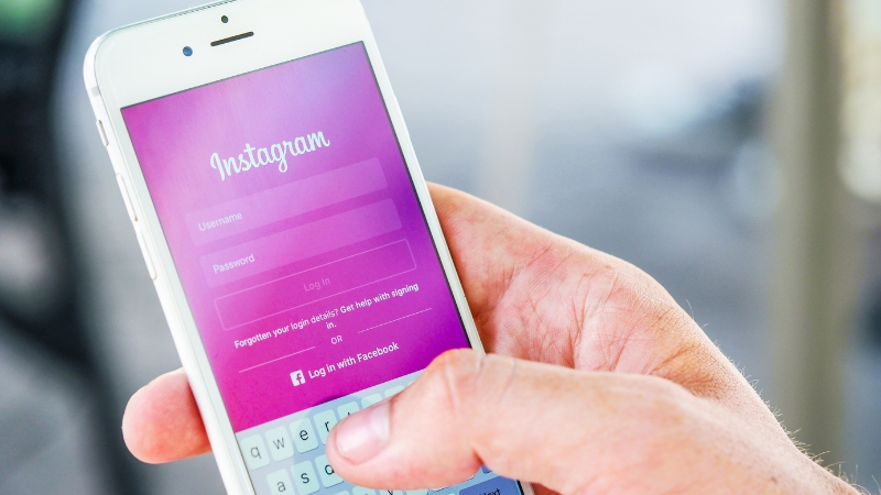 A person holds a smartphone displaying the Instagram login screen