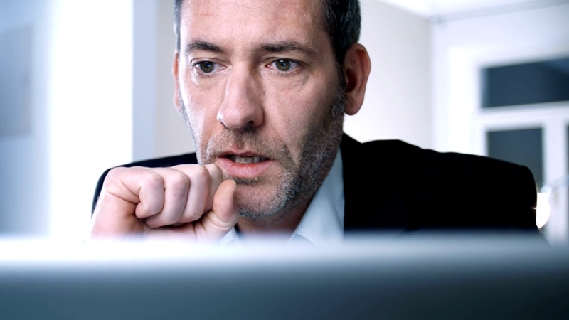 A focused man stares at his screen, reflecting the pressure of managing IT priorities under constant urgency