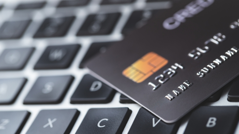 A credit card rests on a laptop keyboard, ready for automated payments
