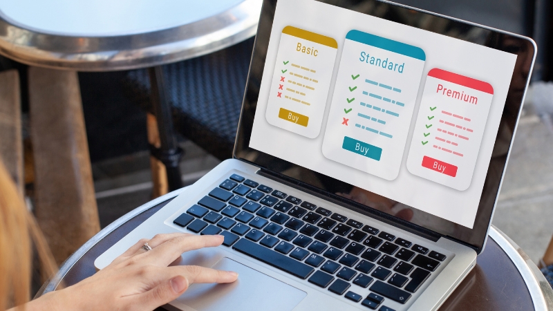 A person looks at a laptop screen showing Basic, Standard, and Premium subscription plans with prices and features