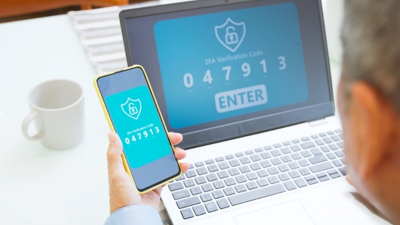 User enters a 2FA security code on a laptop while confirming the login on a mobile phone