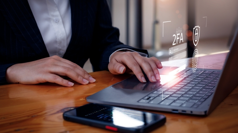 User sets up two-factor authentication on a laptop with a phone placed nearby